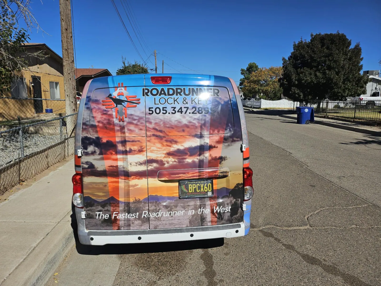 Back of the Roadrunner Lock and Key van on a residential street, with the company name and phone number 505.347.2895